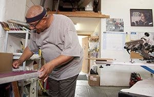 Dismas House resident and Triple Thread employee Dwain Adkins cleans a silk screen to prepare for a custom print job at the shop where he works in Nashville, Tenn., May 1. Triple Thread Apparel was started three years ago by Dismas volunteers to provide employment for ex-offenders who often have trouble finding work because of their felony records. (CNS photo/Theresa Laurence, Tennessee Register)