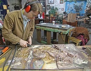 Sculptor Cody Joseph Swanson grinds a weld smooth on a bronze panel for the new doors at Holy Hill on Friday, May 17. (Catholic Herald photo by Steve Wideman)