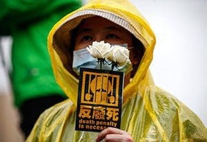 A protester holds a sticker and roses during an April 10 demonstration against the death penalty in Taipei, Taiwan. Pope Francis urged additional support in abolishing the death penalty worldwide and eradicating the external debt of developing countries. (CNS photo/Ritchie B. Tongo, EPA)
