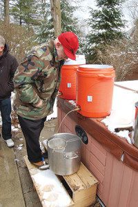 Pete Weingarten checks on the beer that he and fellow members of the Holy Brewers are brewing in his backyard on Saturday, April 2.