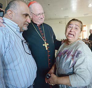 Cardinal Timothy M. Dolan of New York listens to Amal Mare during a visit to a camp for internally displaced families in Ankawa, Iraq, April 9. (CNS photo/Paul Jeffrey)