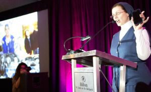 Keynote speaker Sister Helena Burns, a Daughter of St. Paul, holds up her smartphone as she tells Catholic communicators attending a June 3 lunch at the 2016 Catholic Media Conference in St. Louis to use social media wisely, meaning, not all the time. (CNS photo/Chaz Muth)