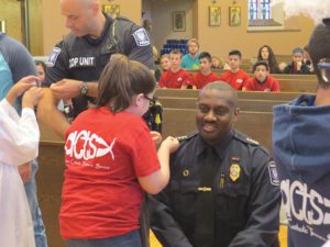 Diana Gonzalez, left, a member of ACTS, (Active Catholics Teens in Service), a Racine-area youth group, pins a lapel pin of St. Michael, the patron saint of police officers, on the uniform of Racine Police Chief, Arthel Howell during a Blue Mass celebrated at St. Richard Parish, Racine, on Friday, May 20. (Submitted photo courtesy Eloy Contreras)