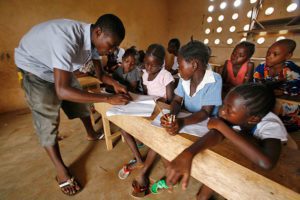 An English teacher works with children in 2010 at a school in Pujehun, Sierra Leone. Father Peter Konteh has appealed to the sponsors of the new U.N. educational initiative to help the children of Sierra Leone, victims of a bloody 10-year civil war and more lately Ebola, return to school. (CNS photo/Ahmed Jallanzo, EPA)