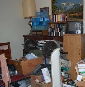 Pictured is the main room of one of Catholic Charities clients. The social service organization is working with the owner to help him address his hoarding disorder. One of their goals will be to remove the belongings on the man’s bed so he can once again sleep in it. The bed is located at left near the window. (Catholic Herald photo by Maryangela Layman Román)