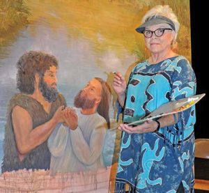 Artist Kitty Lynne Klich, a member of Blessed Trinity Parish, Sheboygan Falls, puts the finishing touches on a lifesize painting of the Baptism of Jesus, June 24. She created the image for St. John the Baptist School, Plymouth. (Catholic Herald photo by Sam Arendt)