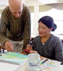 Tony Handzlik, a 95-year-old artist, critiques a watercolor being painted by Ling Naiva at Hart Park Square,  Wauwatosa, Tuesday, Oct. 11. (Catholic Herald photo by Allen Fredrickson) 