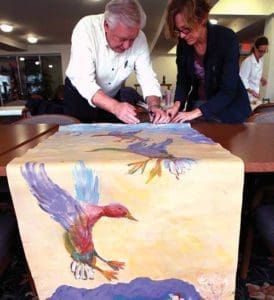 Coordinator Paul Bina and Jenny Farr work on one section of a four-part mural being done by members of Hart Park Square, Wauwatosa, Tuesday, Oct. 11. The artwork will be on display at St. Bernard Parish, Wauwatosa, during the Nov. 5 VIP event. (Catholic Herald photos by Allen Fredrickson)