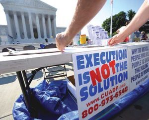 A member of the Abolition Action Committee hangs a sign in front of the Supreme Court in Washington during a 2008 vigil to abolish the death penalty. (CNS photo/Shawn Thew, EPA)