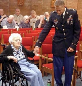 Gregg Haak, a member of the Valor Guard, joins hands with Florence Adamski Gaszak during the opening prayer at a ceremony to return a Purple Heart awarded to her father, Private Boleslaw Adamski, during his service in World War I. The ceremony took place at Clement Manor, Greenfield, Aug. 26. (Catholic Herald photo by Allen Fredrickson)
