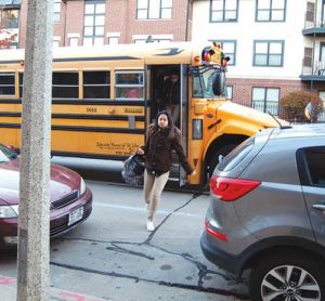 A student exits a bus and heads into St. Joan Antida High School, Milwaukee, on Monday morning, Nov. 21. The school has officially notified the Milwaukee Public School District of its intention to bring suit against them if the district does not begin providing transportation for their students to and from school. (Catholic Herald photo by Joe Poirier)
