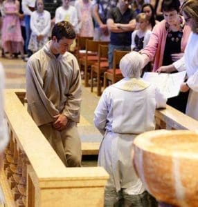 Andrew Landerholm listens as Fr. Jeff Haines, rector and pastor of the Cathedral of St. John the Evangelist, Milwaukee, reads the Rite of Baptism during the Aug. 6 Mass at which the MSOE student received the sacraments of initiation. (Catholic Herald photos by Peter Fenelon)