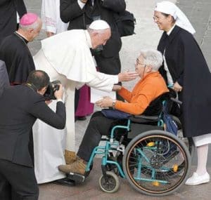 Pope Francis presents his apostolic letter, “Misericordia et Misera,” (Mercy and Misery) to a woman in a wheelchair at the conclusion of the closing Mass of the jubilee Year of Mercy in St. Peter’s Square at the Vatican Nov. 20. In the letter the pope called for several special initiatives begun during the Year of Mercy to continue on a permanent basis. (CNS photo/Paul Haring)