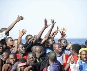 Migrants reach out from a boat during rescue operations Oct. 20 in the Mediterranean Sea. The number of migrants and refugees who have died while making the treacherous journey across the Mediterranean is expected to reach an all-time high in 2016, according to the U.N. Refugee Agency. (CNS photo/Italian Red Cross via EPA)