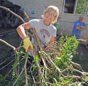 As Ron Rowe looks on Nan Gellings clears brush from the Rowe yard on Sunday, Sept. 18. Members of the Shepherd of the Hills, Eden community pitched in to help the Rowe family with yard work and renovations to the home to make it accessible for Tara Rowe. (Catholic Herald photo by Sam Arendt) 