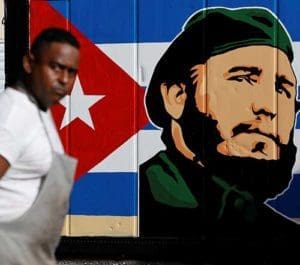 An employee of a state-owned candy store looks outside near a painting depicting Cuba’s former President Fidel Castro, following the announcement of Castro’s death, in Havana, Nov. 27. Castro, who seized power in a 1959 revolution and governed Cuba until 2006, died Nov. 25 at the age of 90. (CNS photo/Reuters)